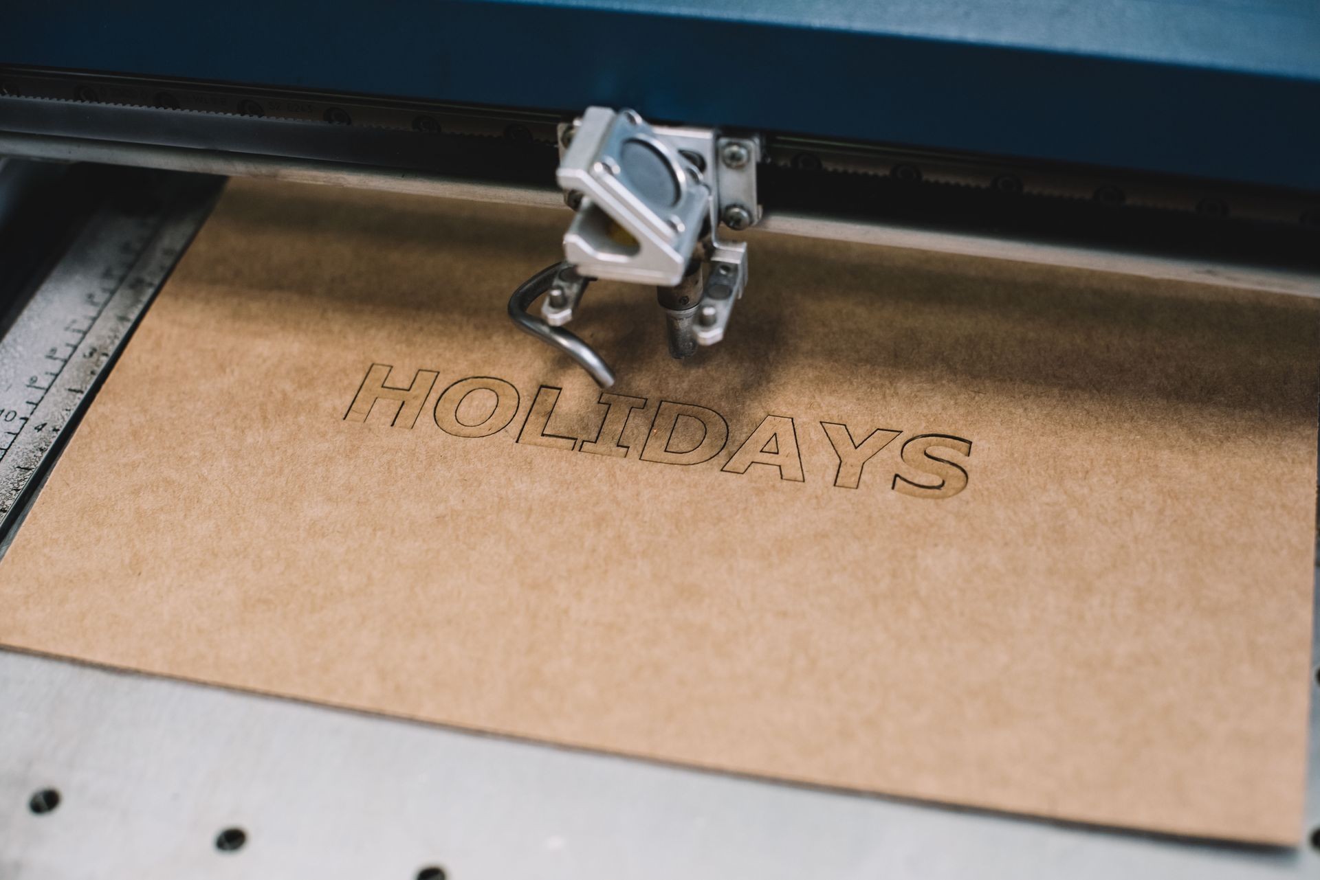 Industrial laser engraving word "holiday" on a cardboard, process Industrial laser engraving word "holiday" on a cardboard, process